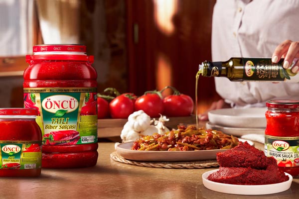 Öncü pepper paste and olive oil beside a freshly prepared meal
